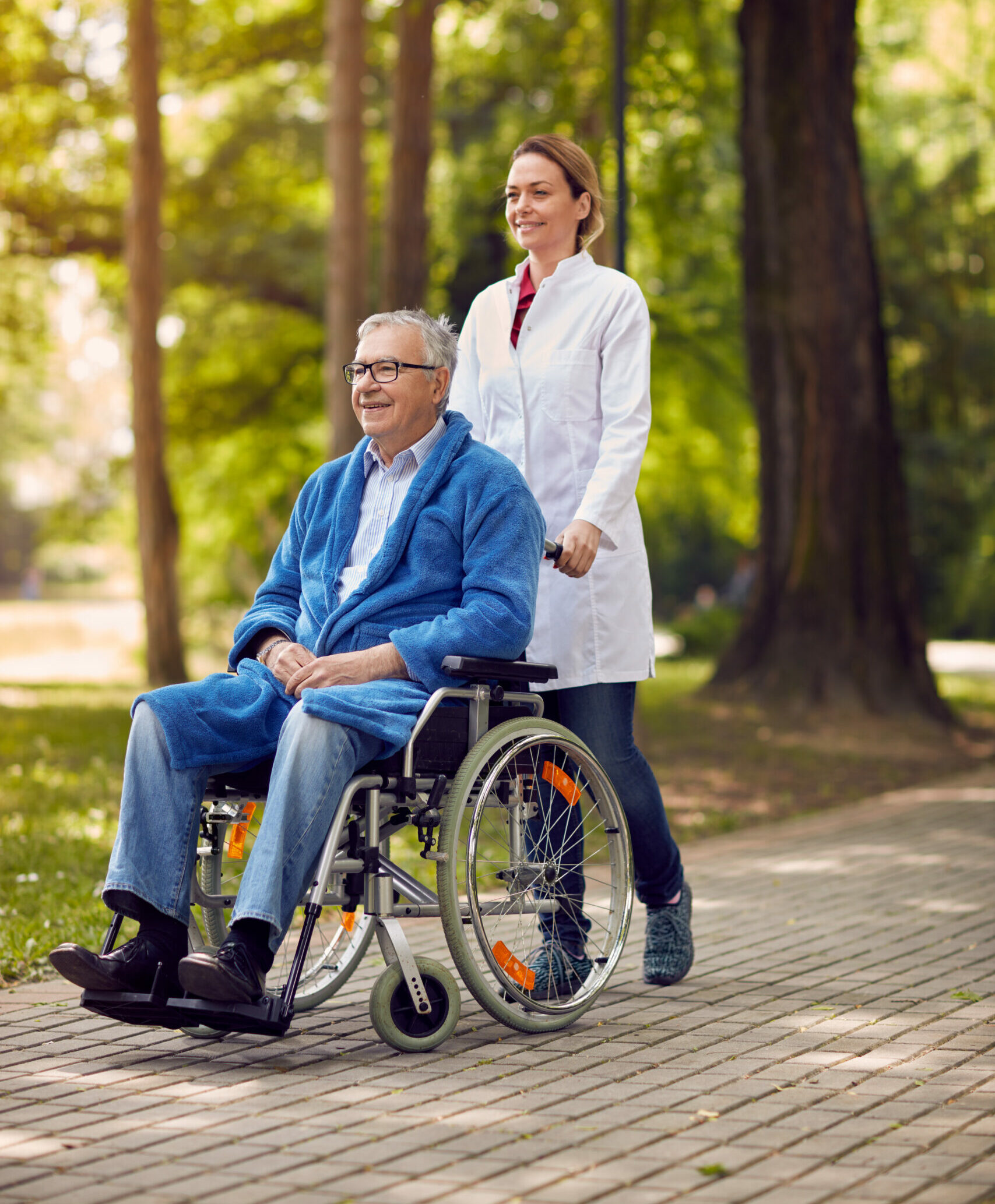 elderly man on wheelchair with caregiver nurse outdoor